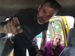 A man holding a frog inside a van