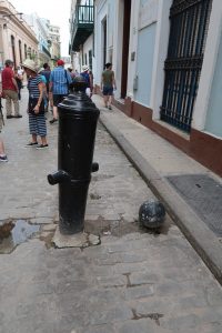 A cannonball and an upside-down cannon that have been cemented into the brick street