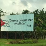 A billboard with an image of a Cuban flag saying, "Somos y debemos ser socialistas. Fidel."