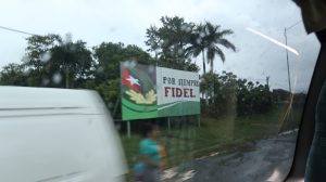 View from a van window of a sign that reads, "Por Siempre Fidel"